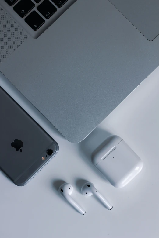 an iphone and ear buds are sitting next to an apple laptop