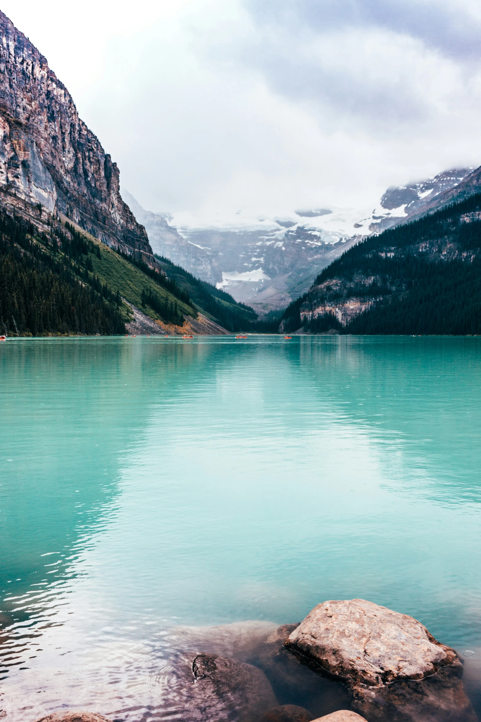 a green lake with snow covered mountains in the background