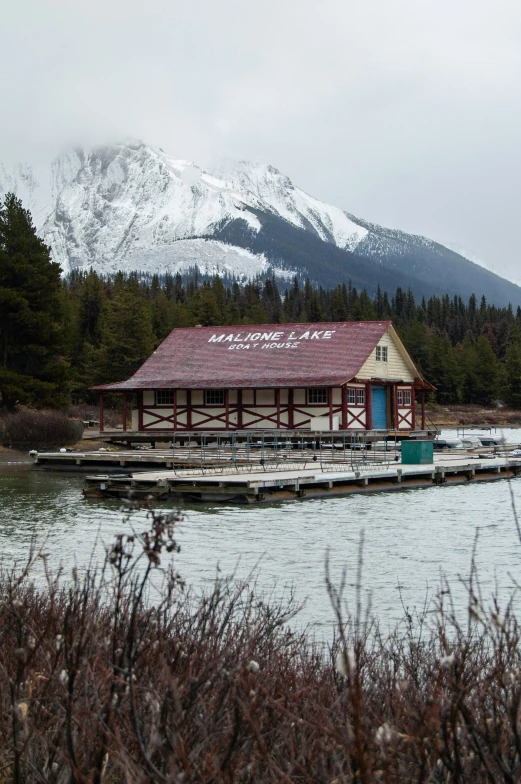 a boathouse is sitting on the water near mountains