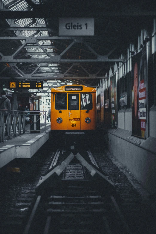 a lone yellow train pulling into the station