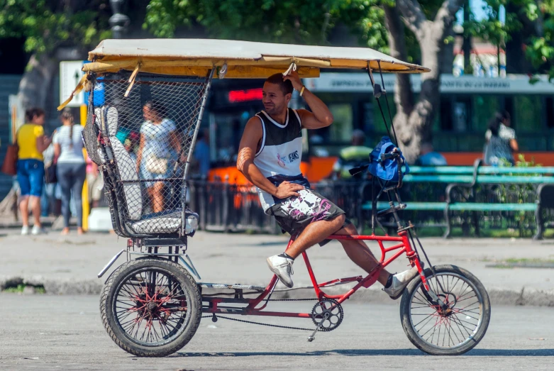 man in white shirt riding a bicycle with a roof attached to it