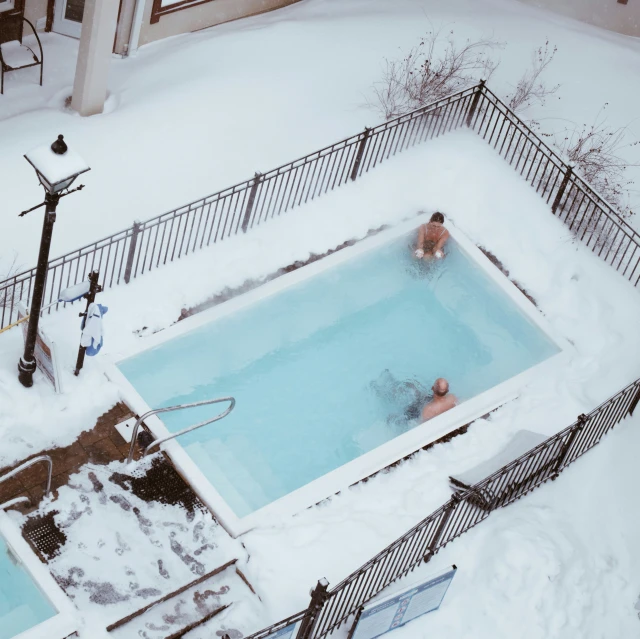 two people are playing in the snow near a swimming pool