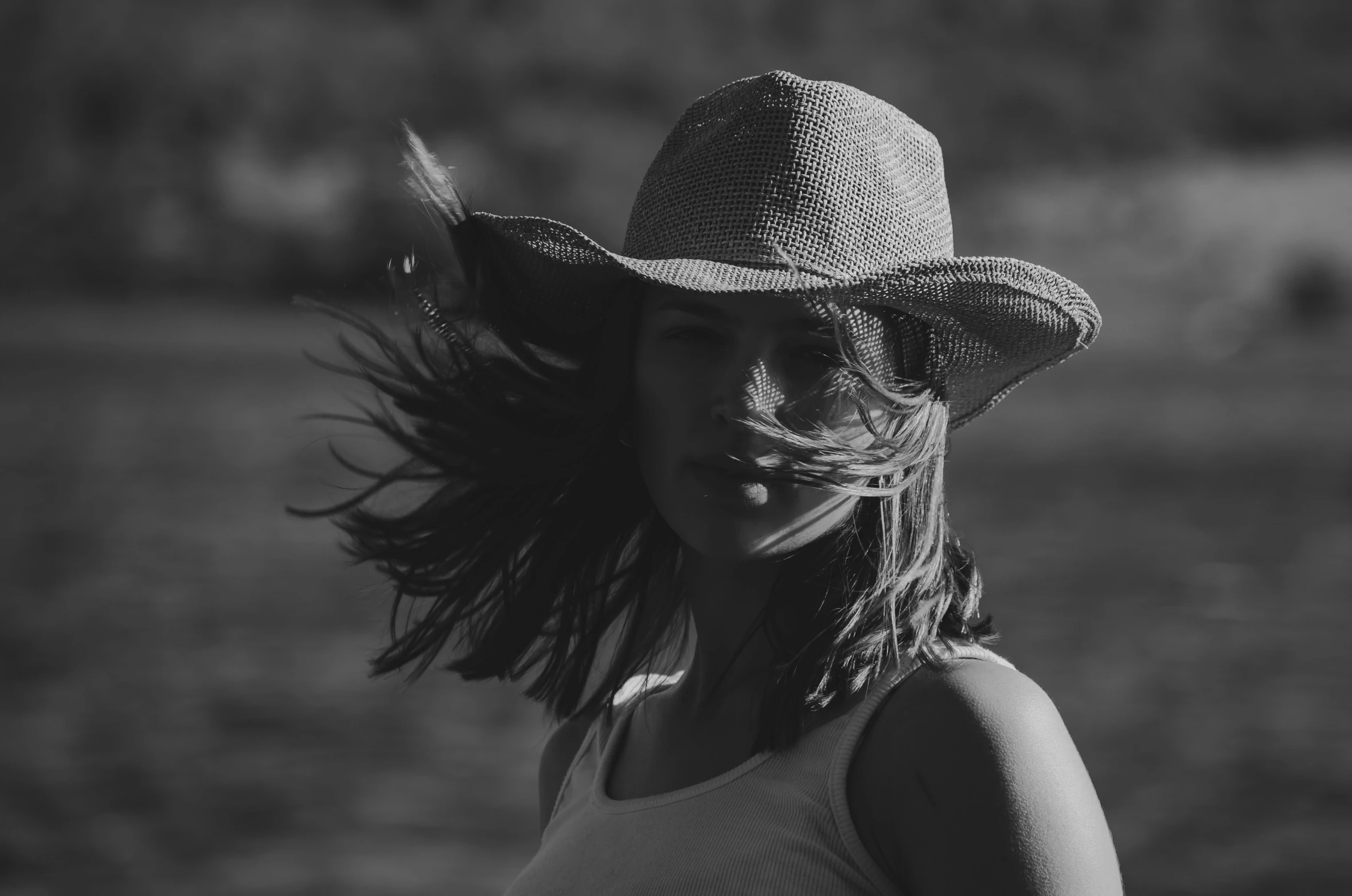 a woman wearing a straw hat in the wind