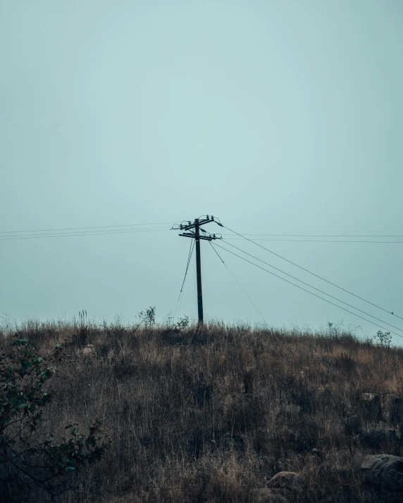 a telephone pole sitting on top of a grass covered hill