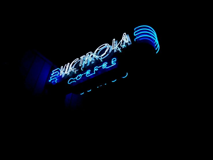 a illuminated neon sign sitting above a sidewalk