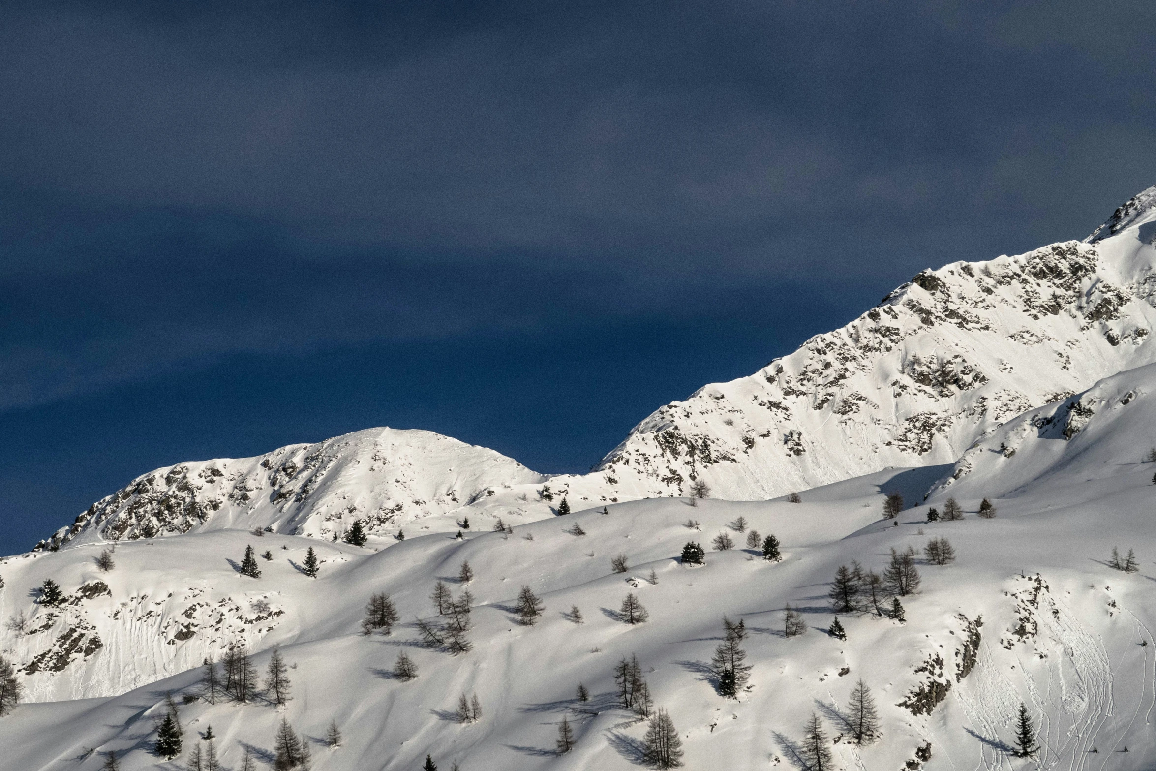 a skier in a red jacket and blue skies is doing his job on the slope