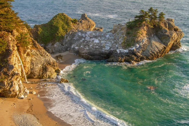 an aerial view of a beach with a large rock formation