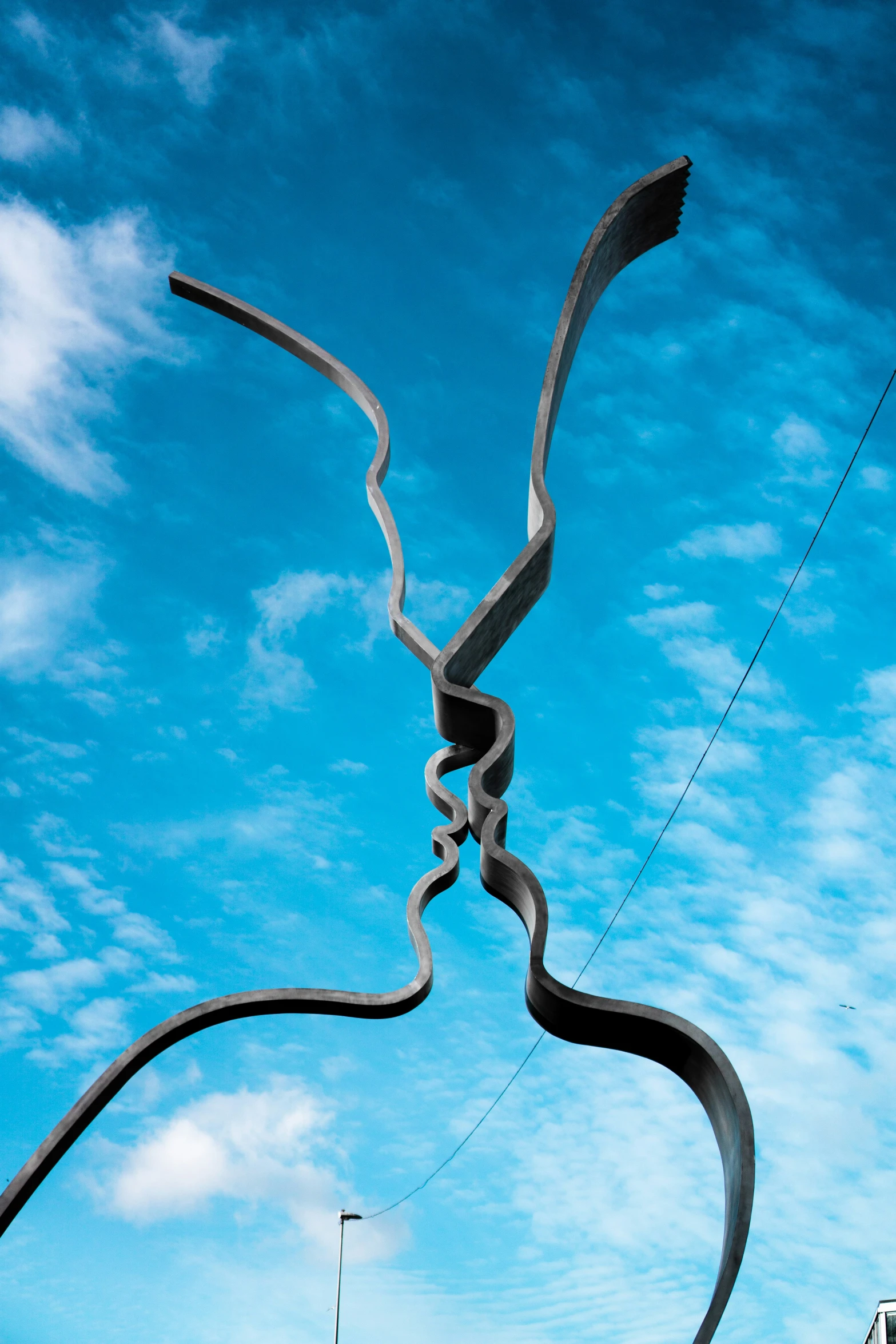 an artistic metal sculpture is shown against a cloudy sky