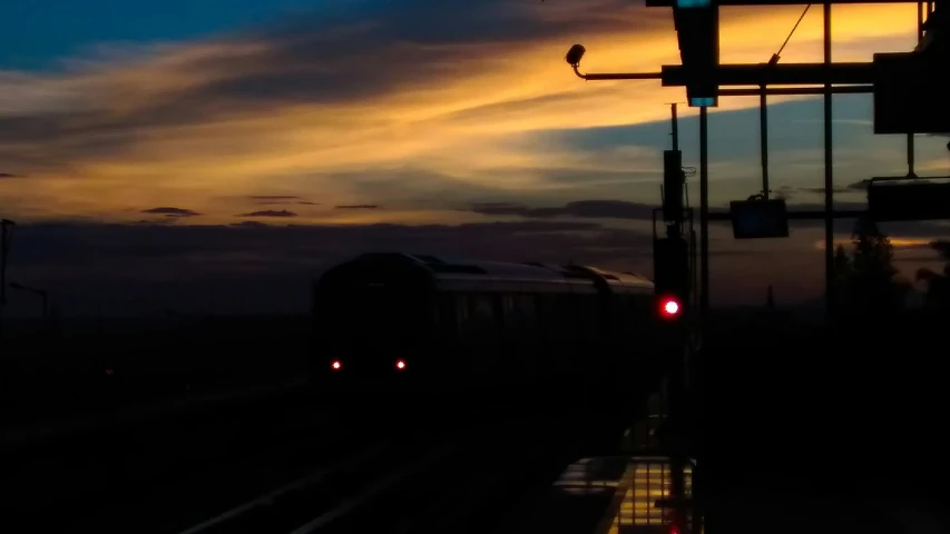 the silhouettes of a train as it approaches a signal at dusk