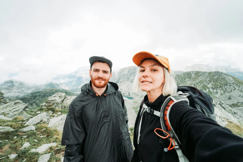 a man and woman posing for a po while standing on top of a mountain