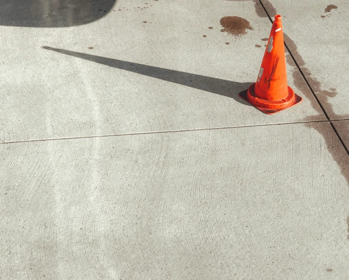 an orange cone that is on the ground next to a sidewalk