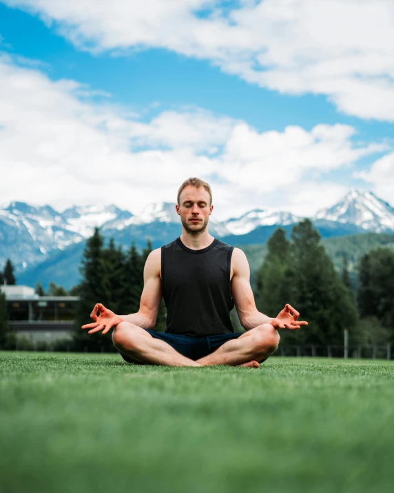 a man meditating in the middle of the grass