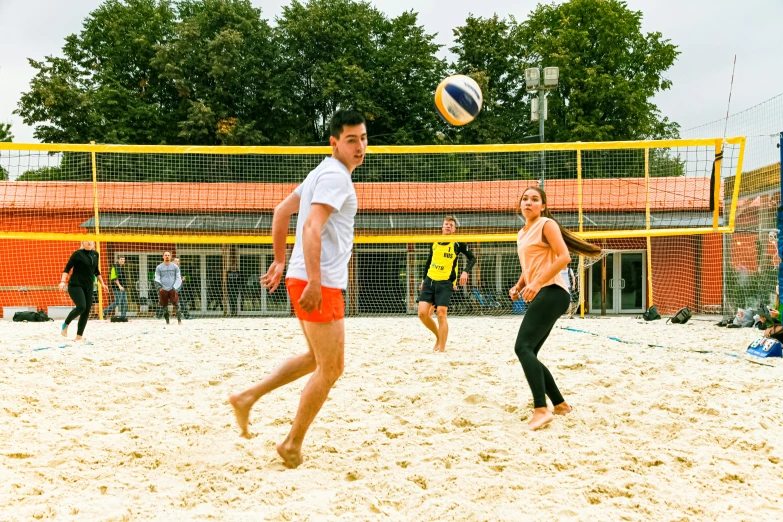 the men and women are playing volleyball in the sand