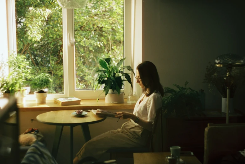 a woman sits on a chair looking out the window