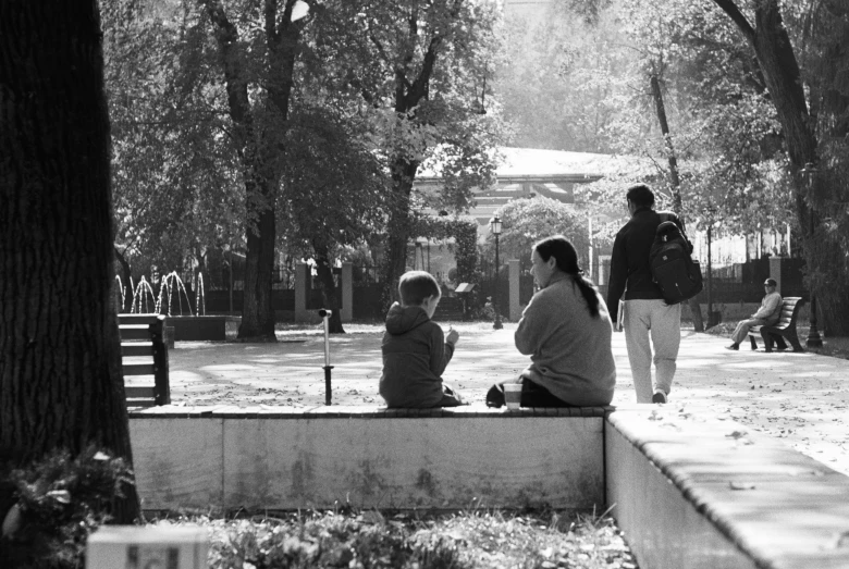 several people sit on benches near trees and benches