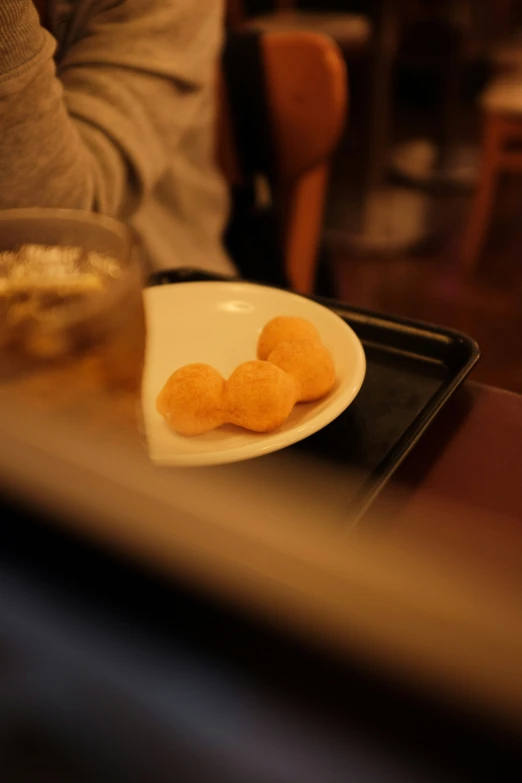 three small pieces of fried food sit on a black tray