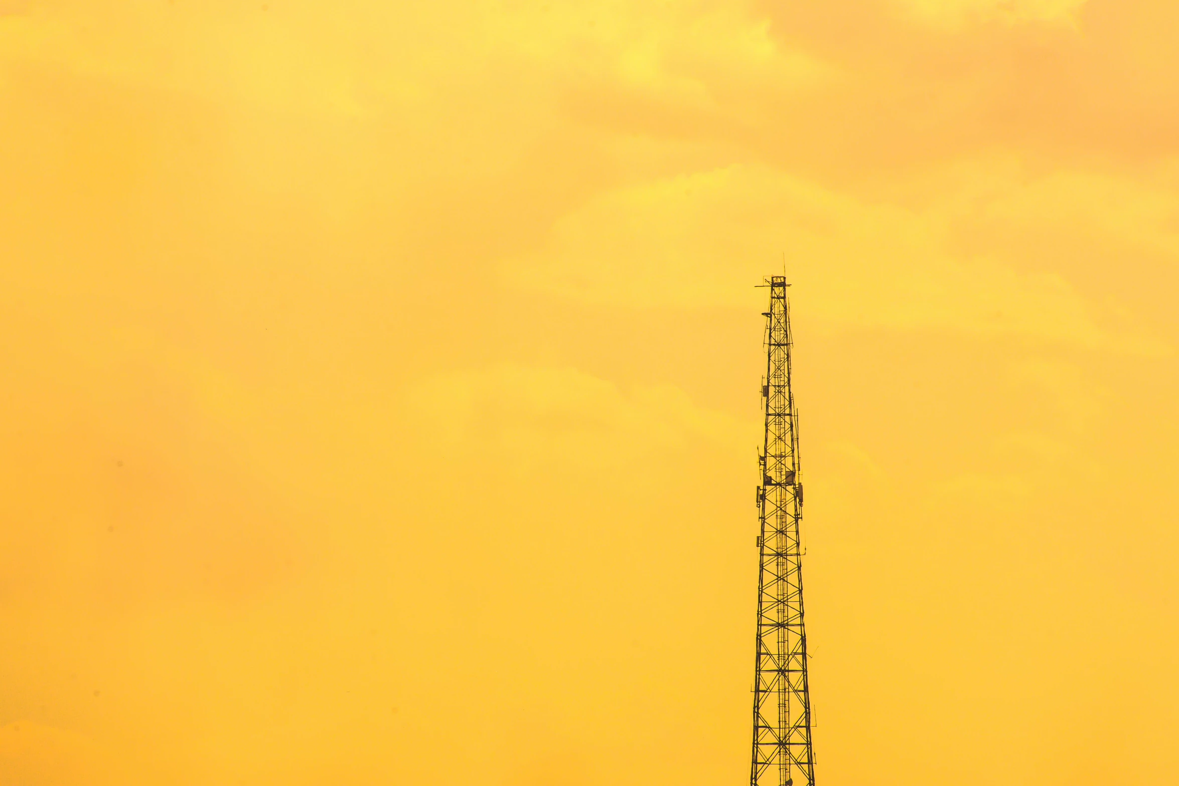 a yellow sky with a cell tower in the distance