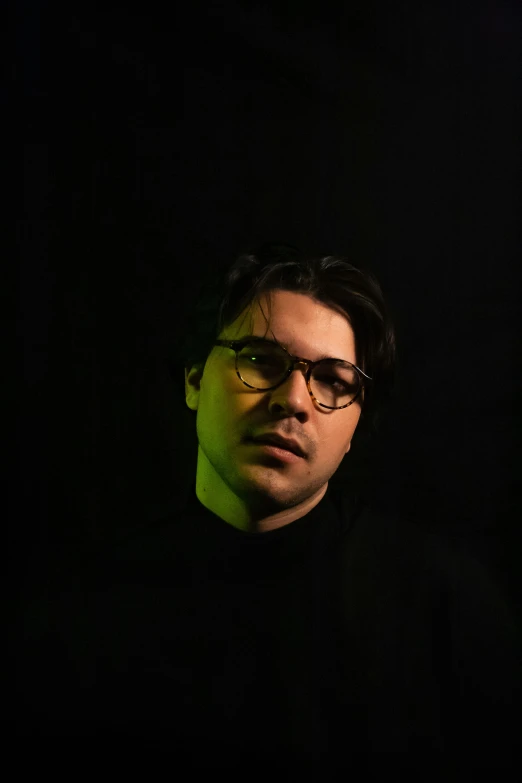 a man in glasses is standing by a wall