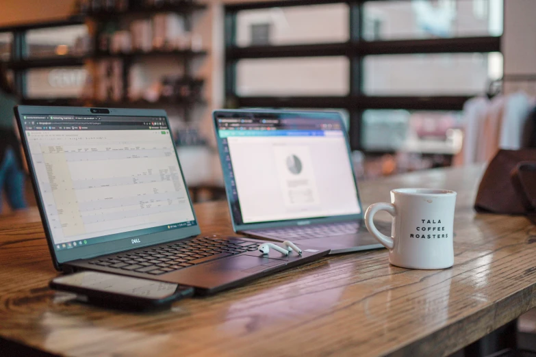 two open laptops on a table in a room with many shelves and shelves