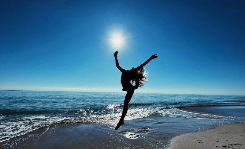 a woman doing a handstand on a beach near the ocean