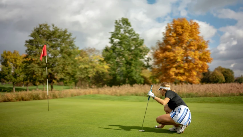 a golf player on a course preparing to put a golf ball