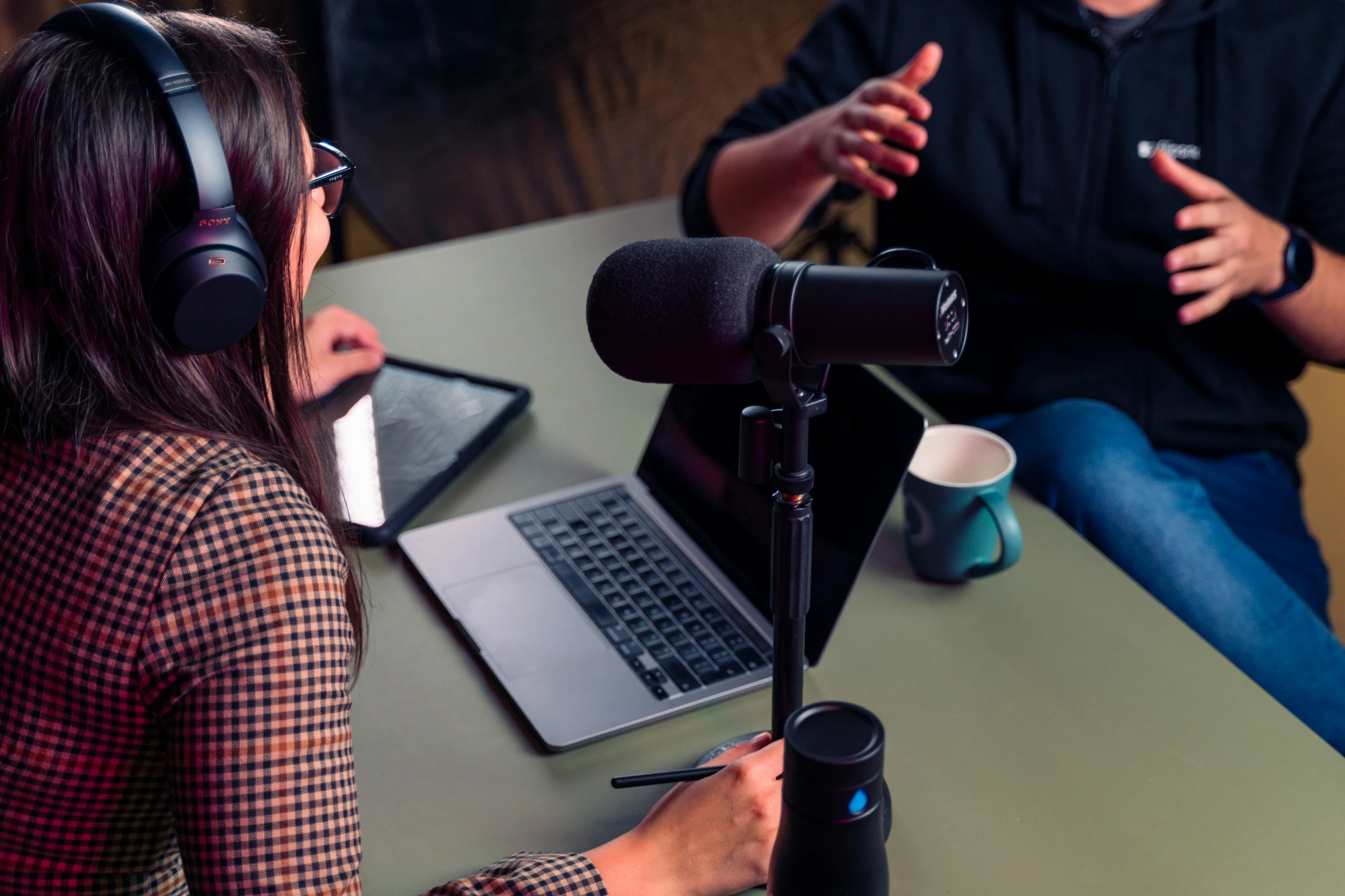 a woman in headphones sitting next to a man in a microphone