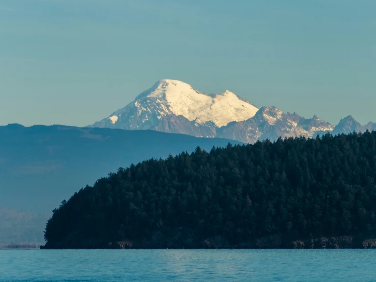 a boat traveling through a lake with a snow covered mountain in the background