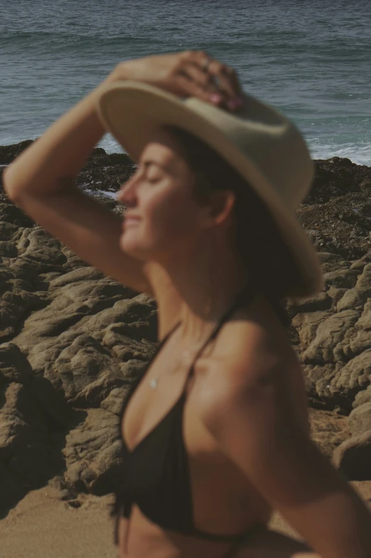 the woman wearing the hat is posing on the beach