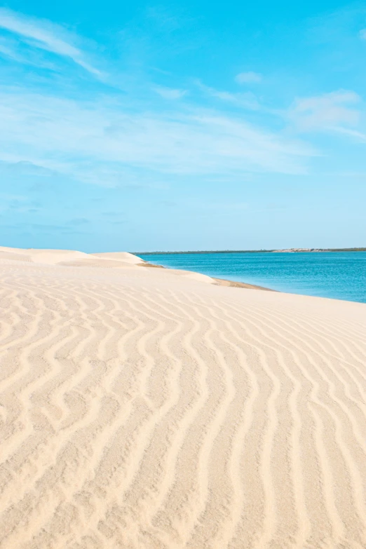 a beach with two people walking across it