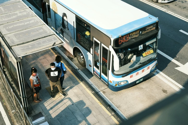 people are boarding a bus at a station