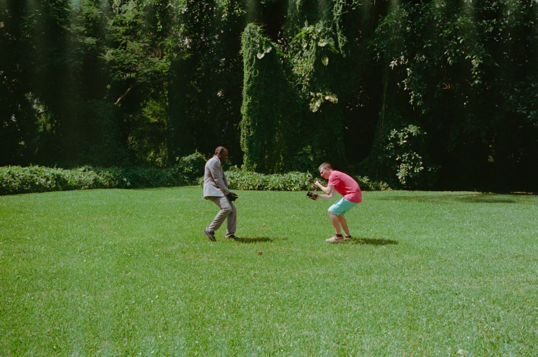 two people playing baseball in a large grassy area