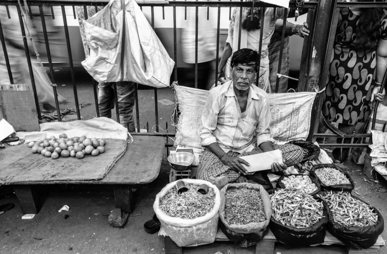 black and white po of a man sitting in an outdoor market