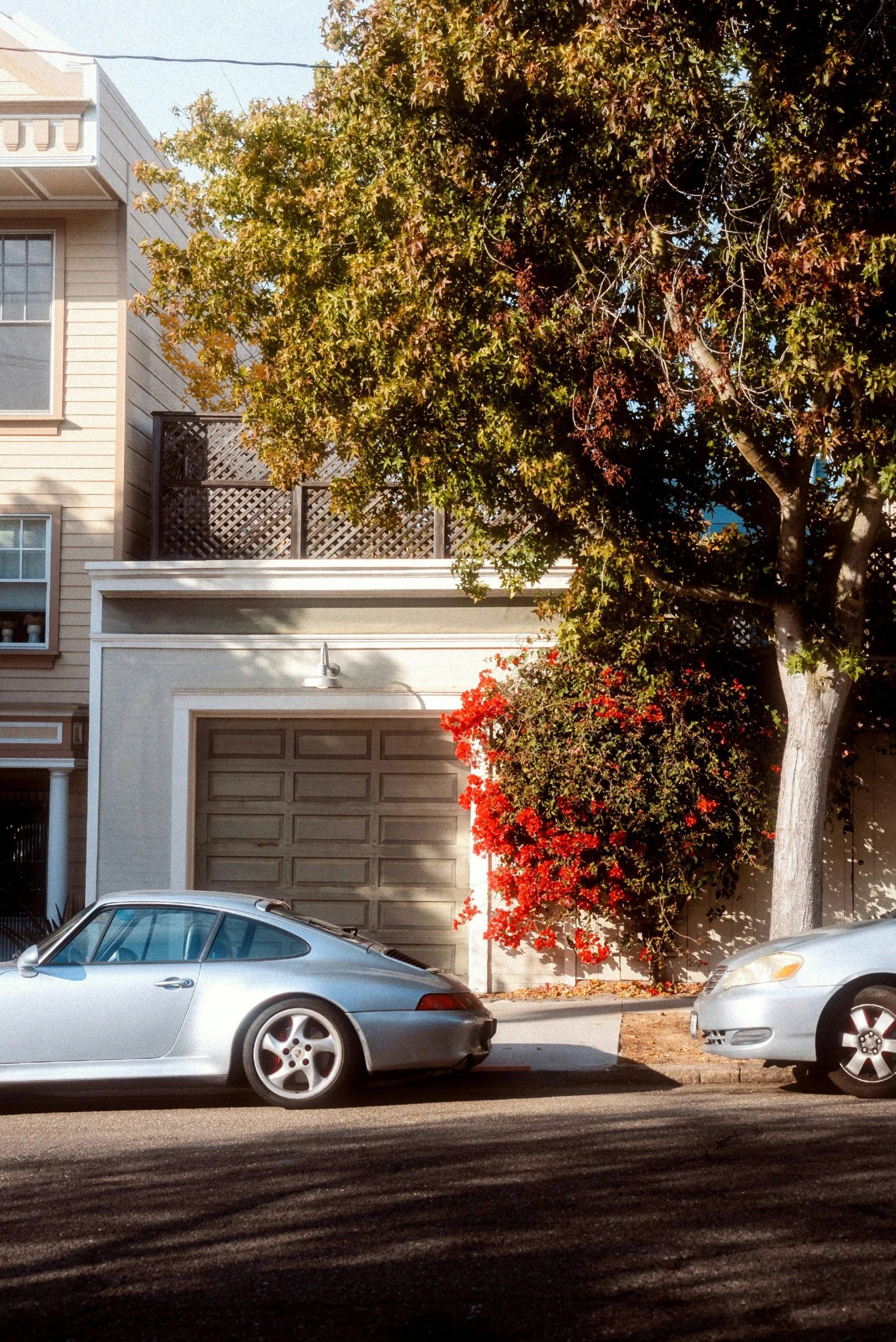 two silver cars parked next to each other in front of a house