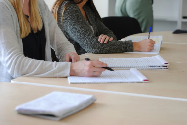 two women sitting at a table with notebooks and notes