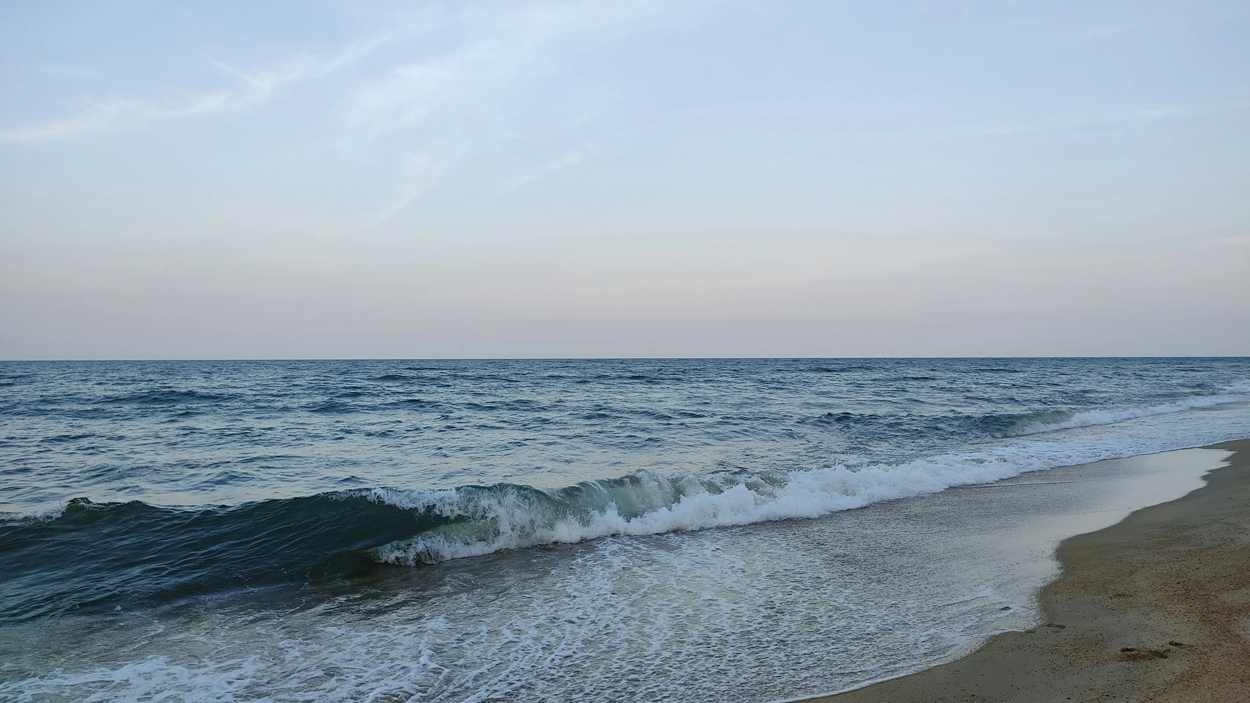 a couple of waves on the side of a sandy beach