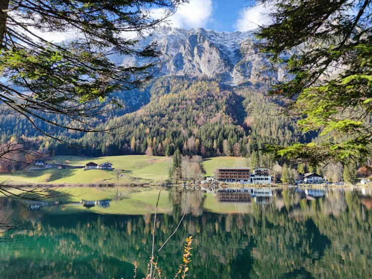 a small hut by some clear water next to a mountain