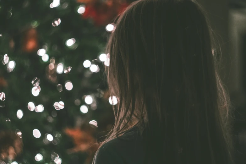 a woman staring into a decorated christmas tree