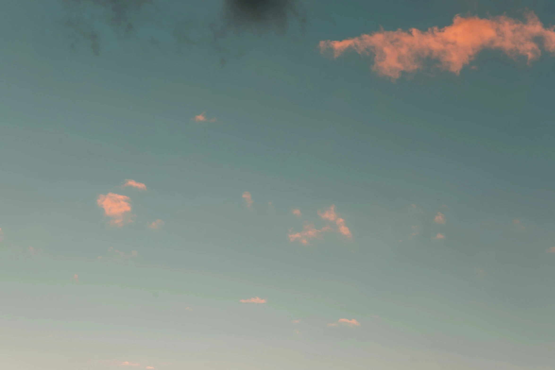 there are pink clouds floating above a blue sky