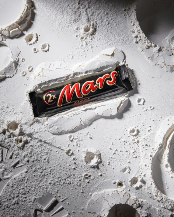 mars chocolate bar laying on the sand with water droplets