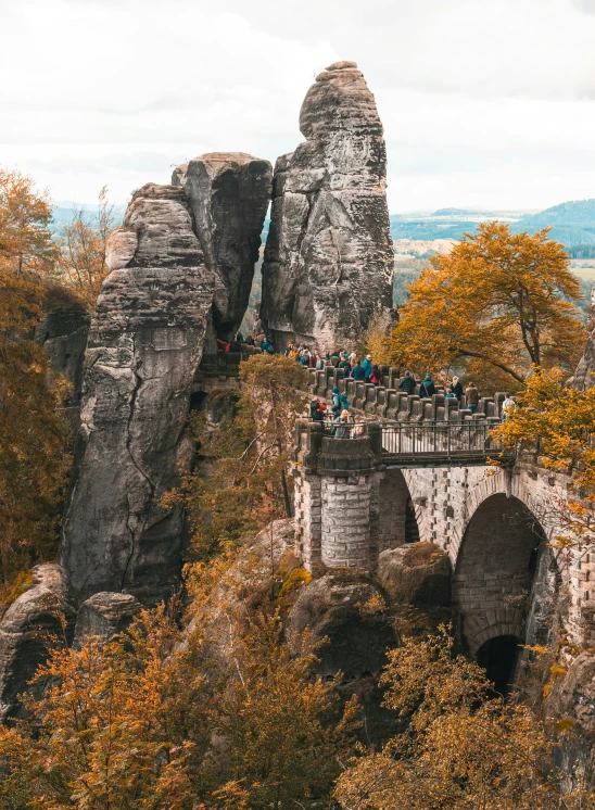 many people are walking over a bridge near the mountains