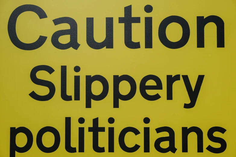a black lettering on a yellow sign says caution slippery politicians