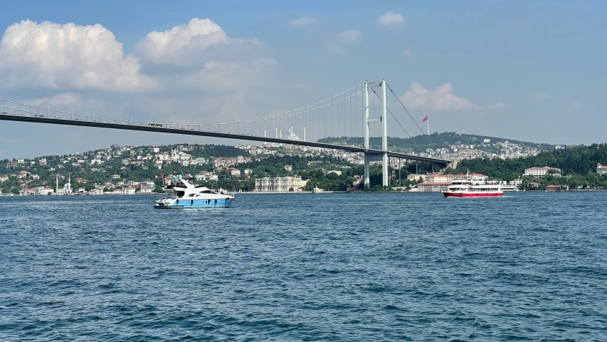 a large bridge spanning over water with two boats in the background