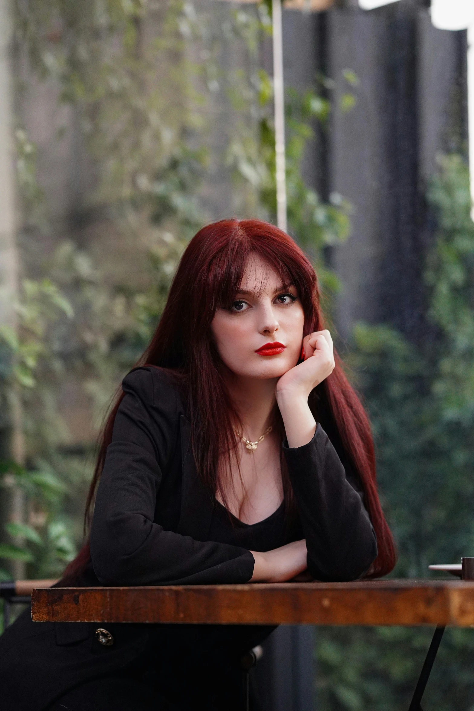 a woman with long hair, sitting at a desk, looking pensive