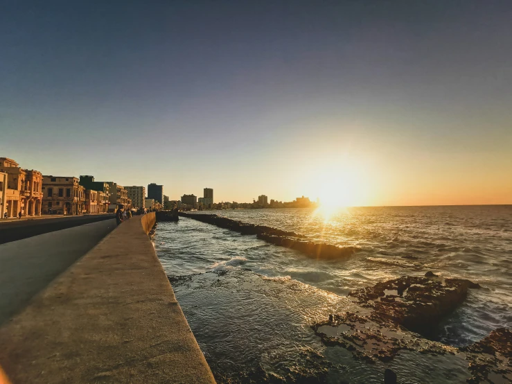 a sun is shining on the ocean with people watching