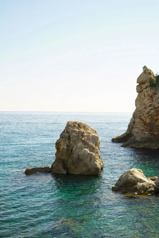 a beach scene with rocks and blue water