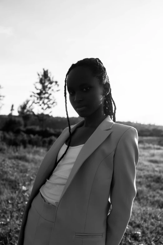 a woman in a suit and tie standing on the grass