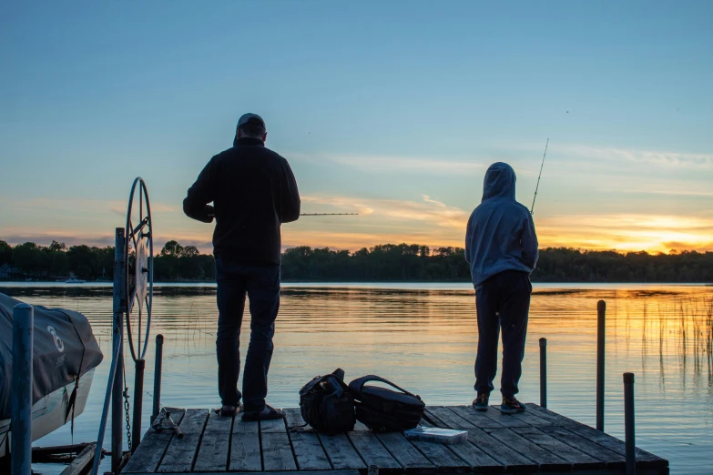 two men standing on top of a dock near the ocean