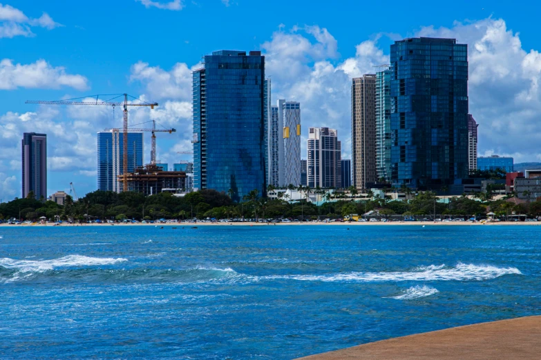 city buildings along side a beach with a small wakeboarder in the foreground