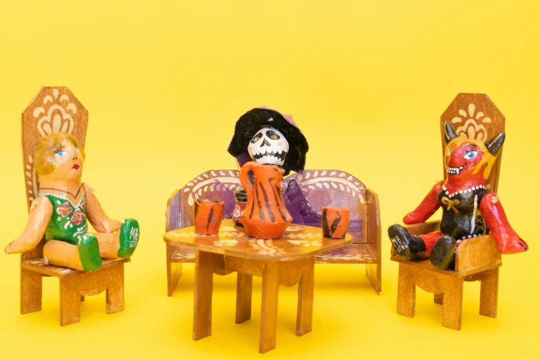 two dollhouse dolls sitting on chairs and a table