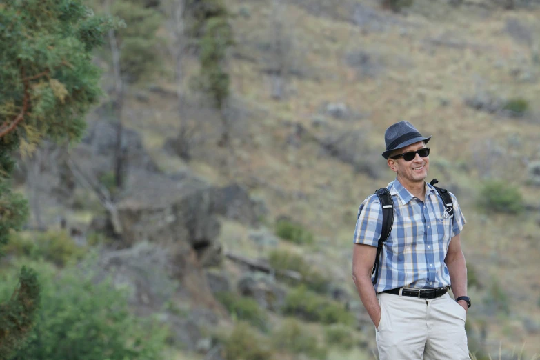 a man in plaid shirt and hat standing near grass